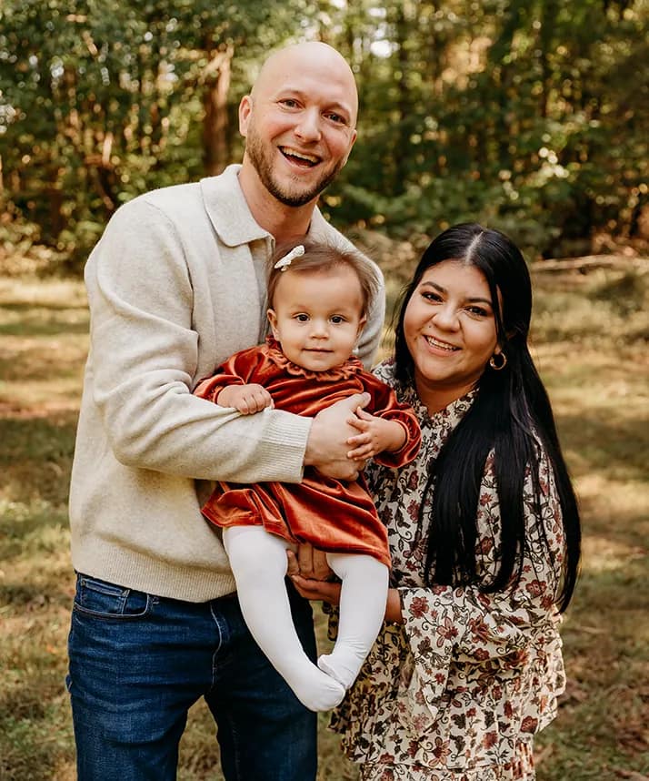 Dr. Daniel Sitzmann standing outdoors with his wife and child