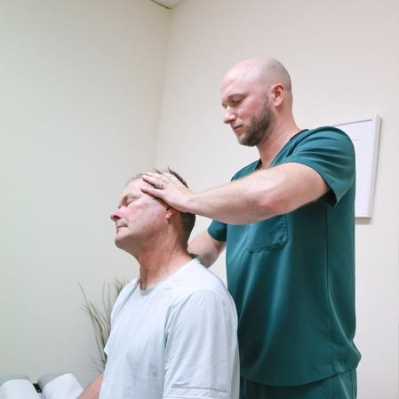 Chiropractor assisting male patient during therapy session