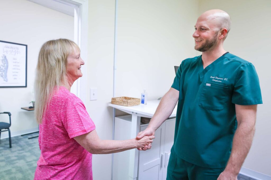 Chiropractor smiling with elderly patient
