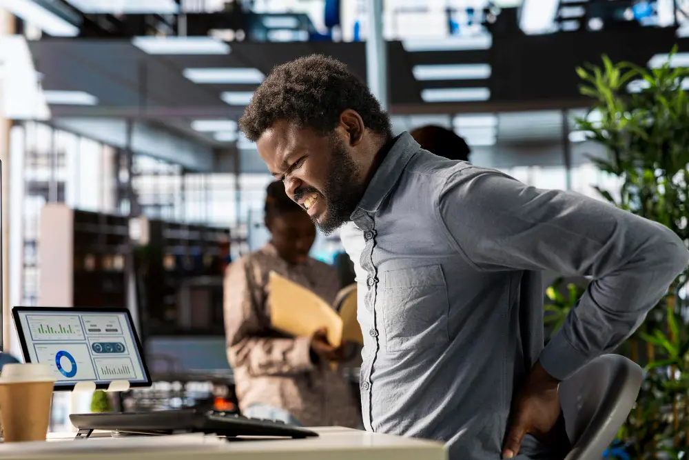 Office worker experiencing neck and back pain from prolonged desk work